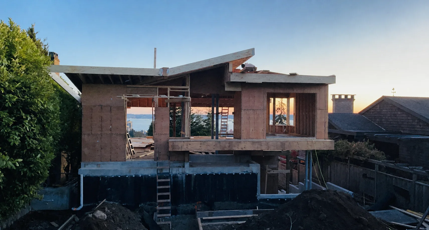 Custom home taking shape during structural framing at sunset